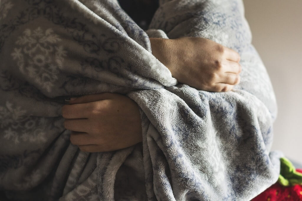 femme souffrante emmitouflée dans un plaid