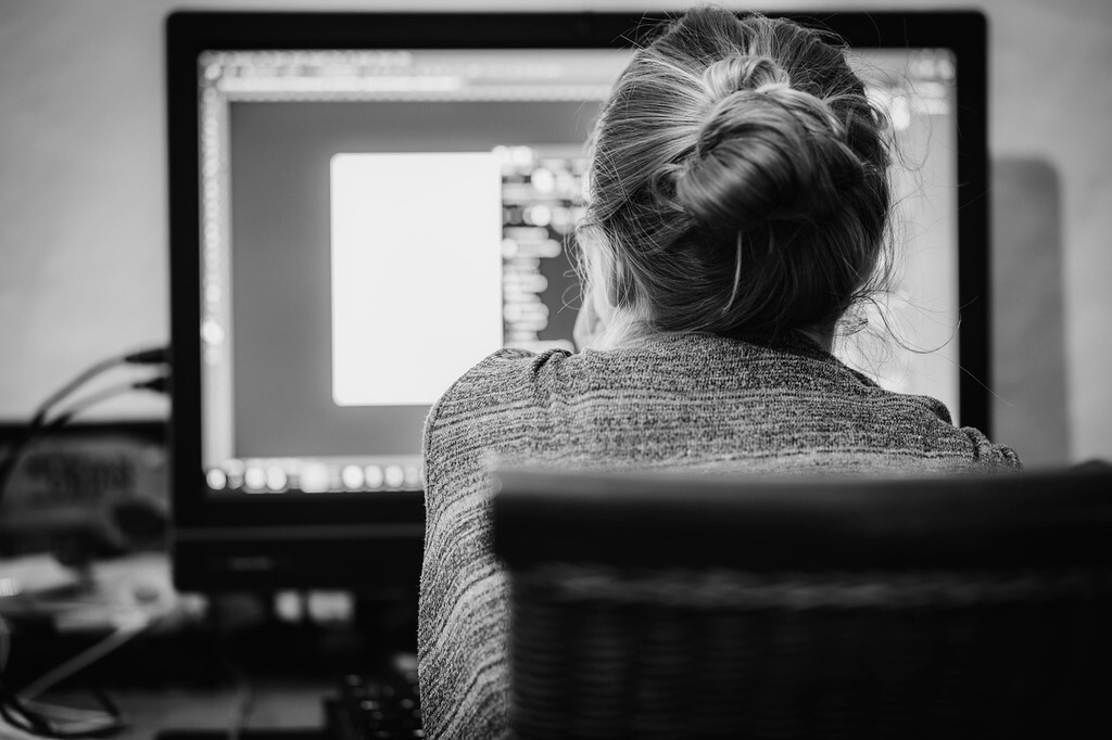 femme de dos en train de travailler devant un ordinateur image en noir et blanc