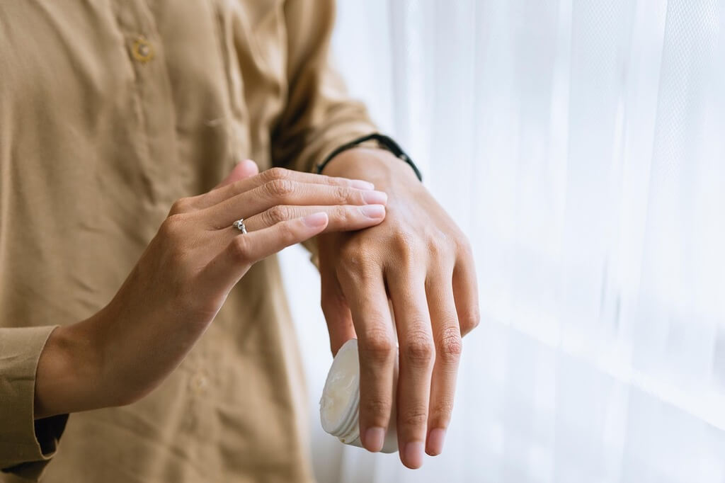 Une femme s'appliquant de la crème sur les mains