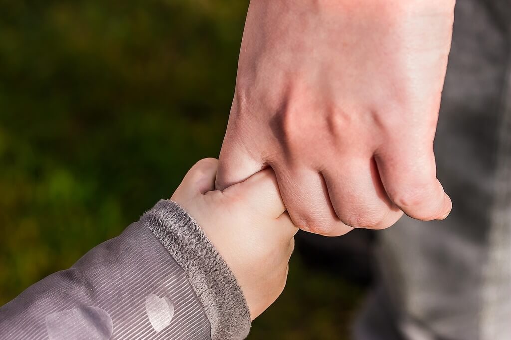 une main d'adulte tenant une main d'enfant
