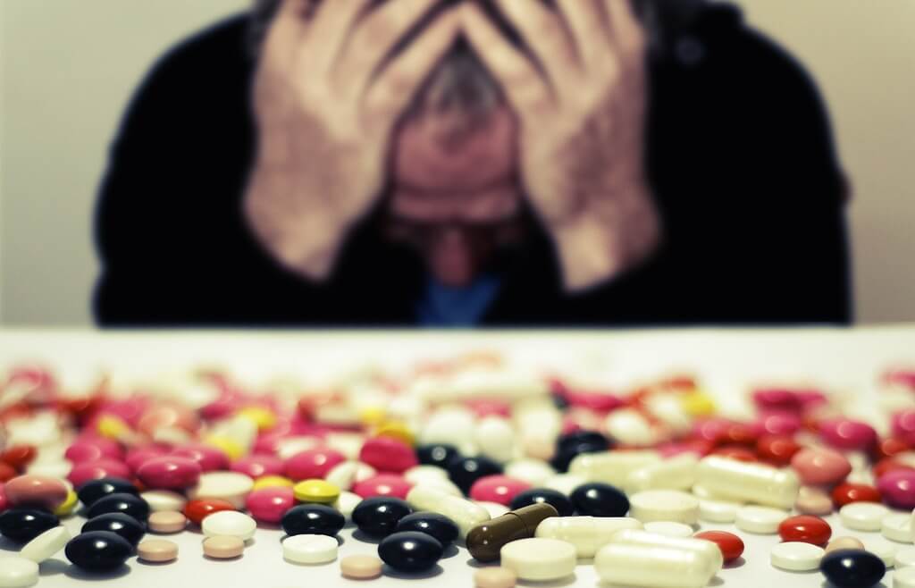 homme souffrant face à ses médicaments